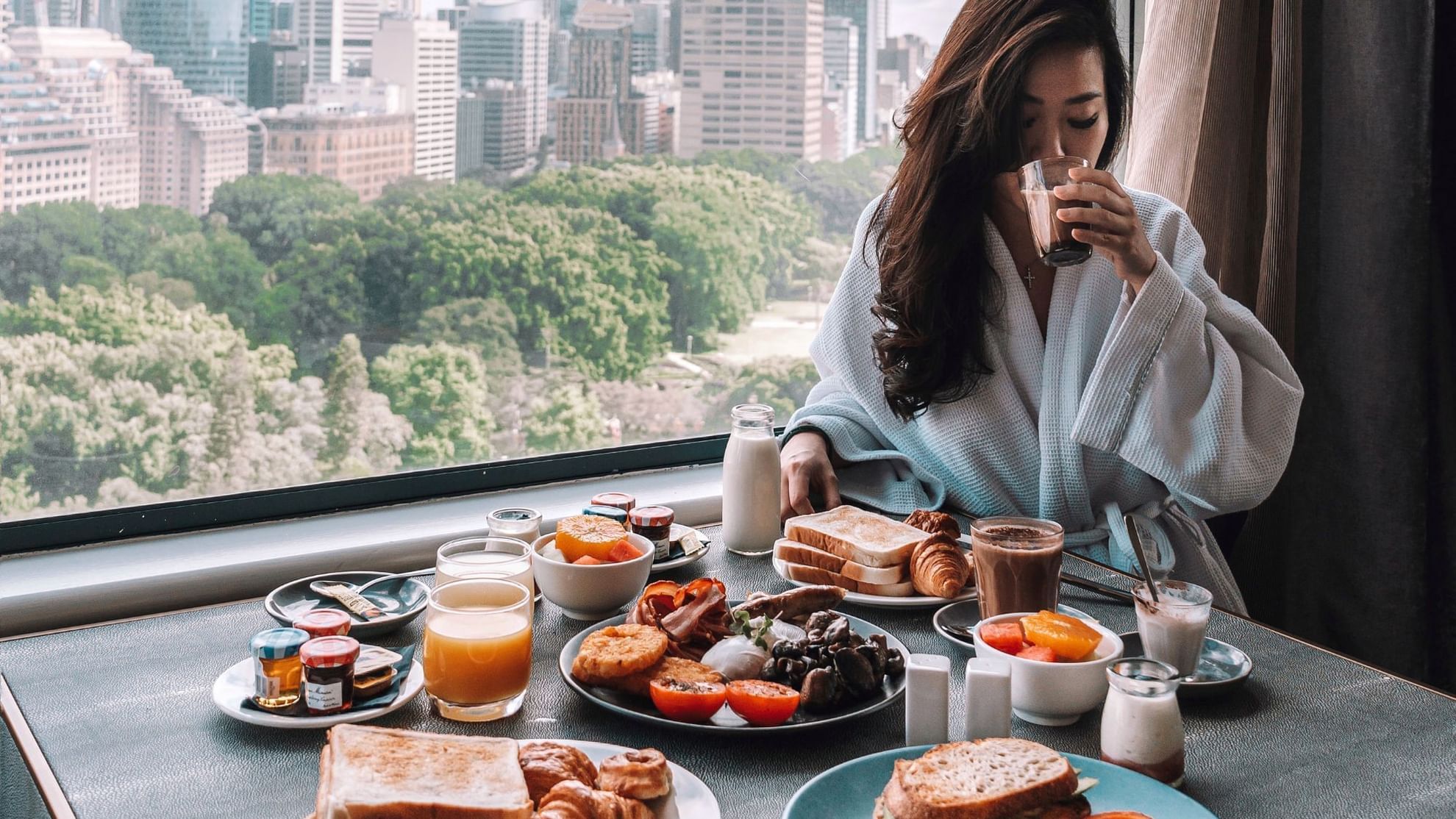 Lady having breakfast in a room with a city view at Pullman Sydney Hyde Park