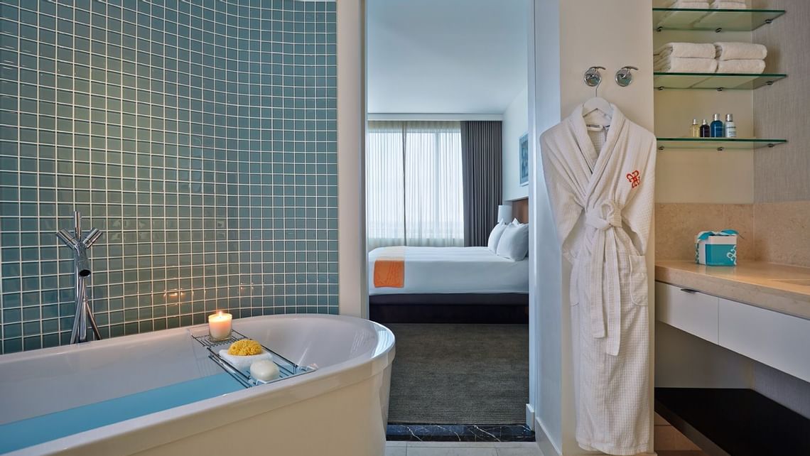 Freestanding bathtub with candle and robe hanging nearby