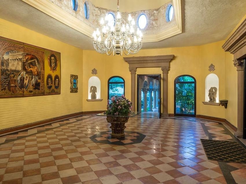 Salón Duque with a grand chandelier, tiled floors, and historic art at Quinta Real Aguascalientes