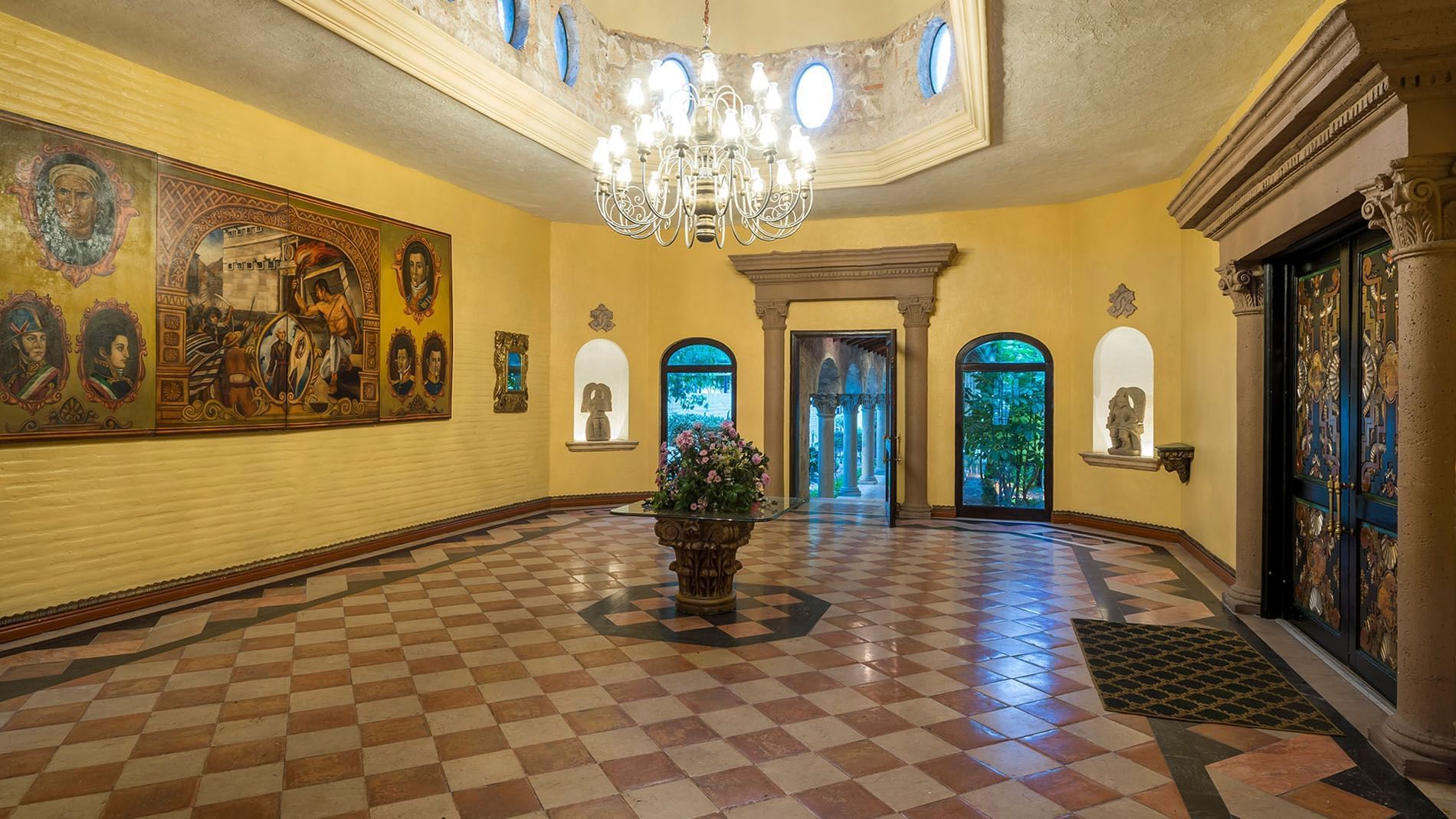 Salón Duque with a grand chandelier, tiled floors, and historic art at Quinta Real Aguascalientes