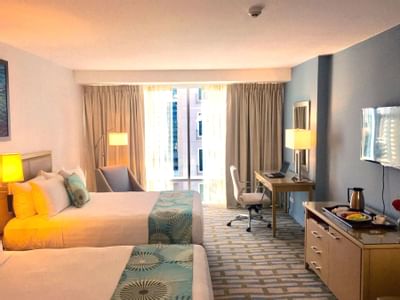 room with two beds, desk and dresser