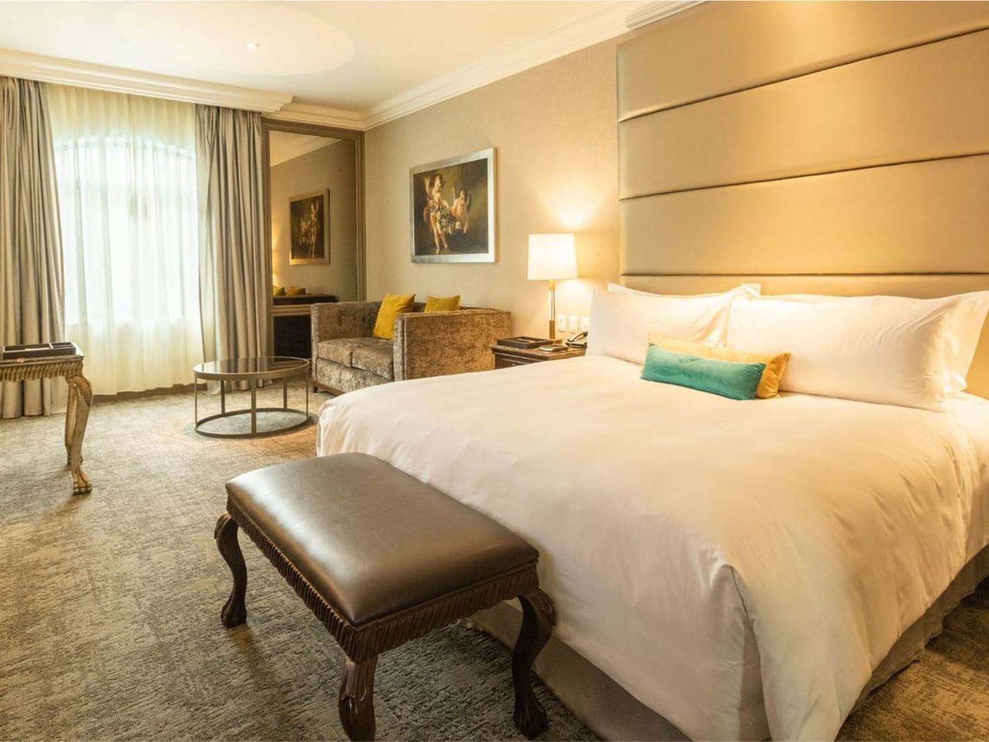 King Grand Class seating area near a large window featuring a velvet sofa and round table at Quinta Real Monterrey