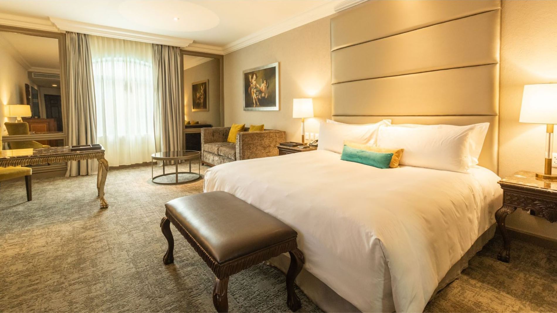 King Grand Class seating area near a large window featuring a velvet sofa and round table at Quinta Real Monterrey