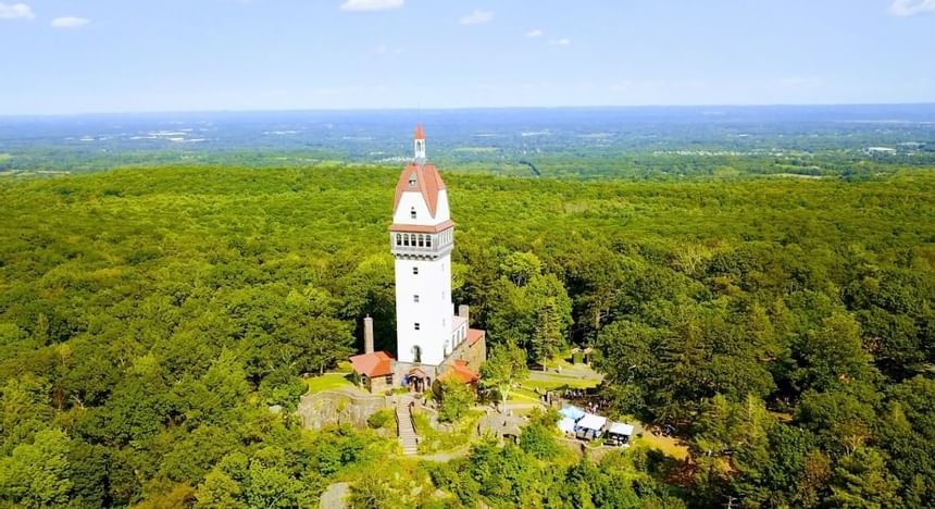 Heublein Tower with a red roof surrounded by dense green forest trees near Talcott Mountain near Avon Old Farms Hotel