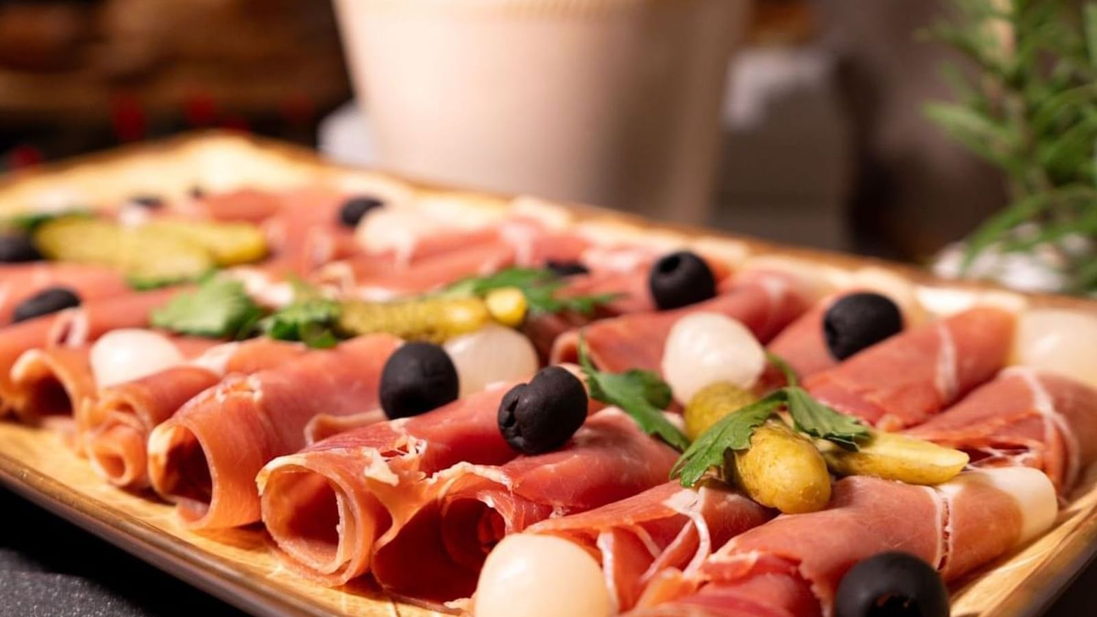 Rolled prosciutto with olives and pickles on a wooden tray in Sunday Brunch at Warwick Paris Champs Elysées