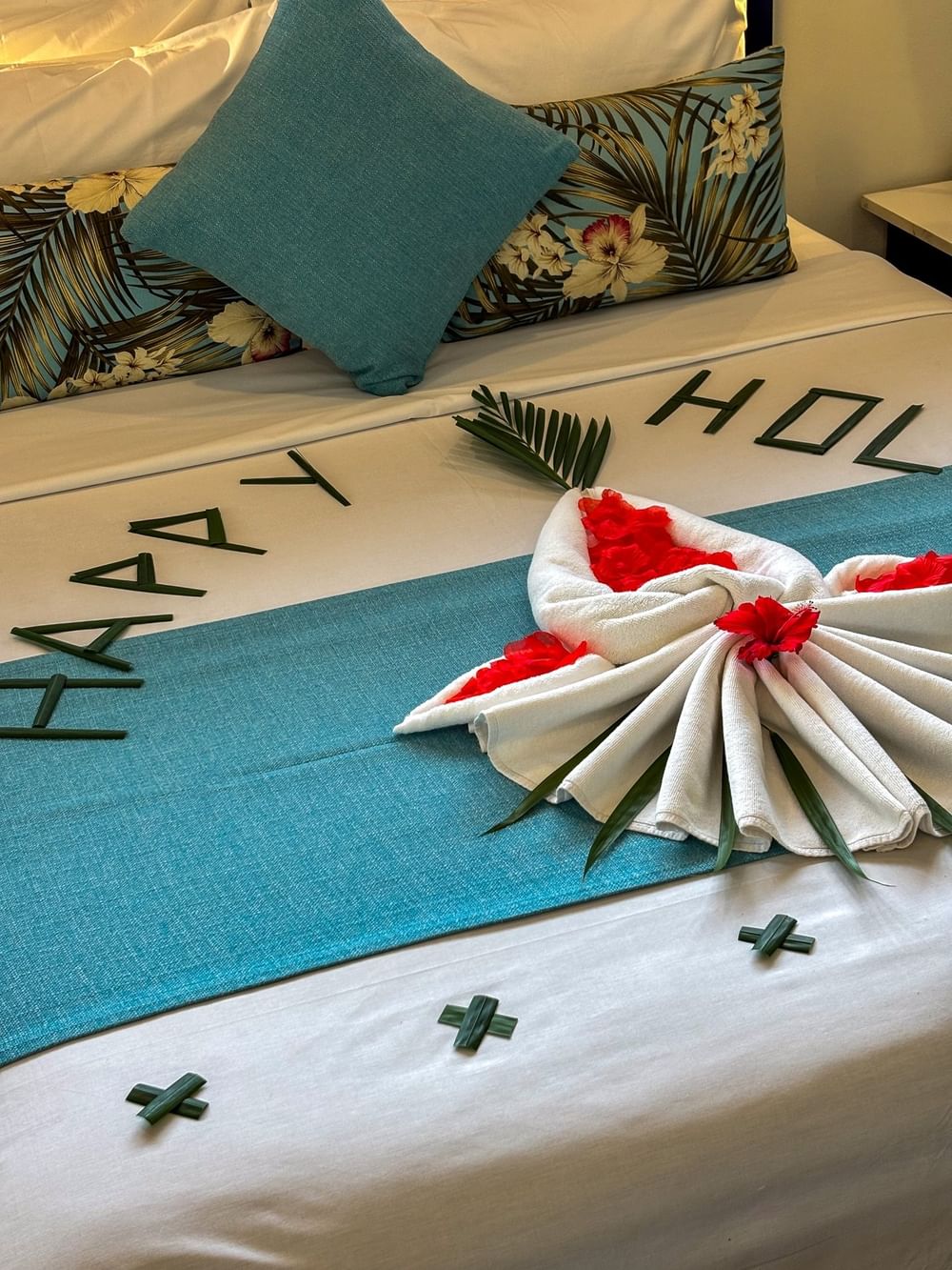 Towel art with red hibiscus flowers by leaf lettering on a bed runner in Family Room at TokaToka Resort Nadi Fiji