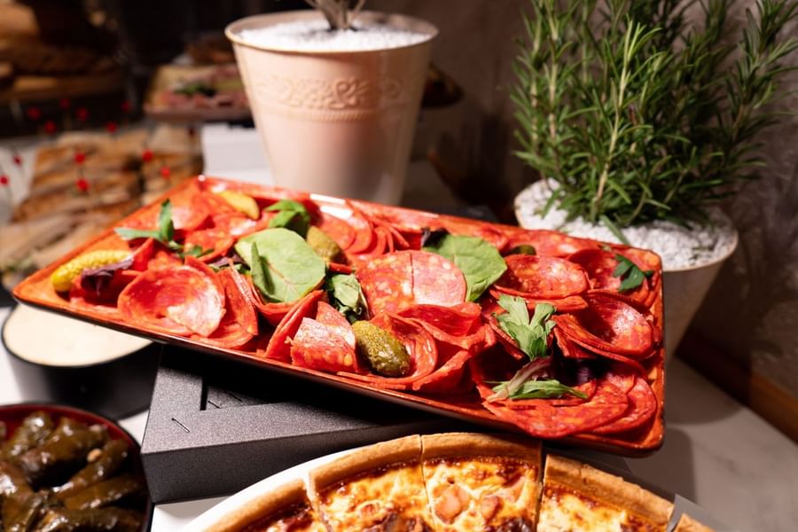 Gros plan sur un plateau de charcuterie agrémenté de feuilles vertes au Warwick Paris Champs-Élysées