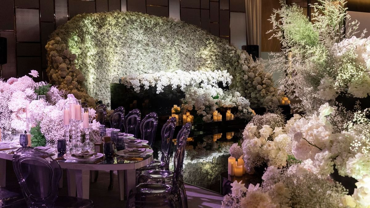 Opulent wedding setup with floral backdrop, candlelit tables and transparent purple chairs at Crown Towers Sydney