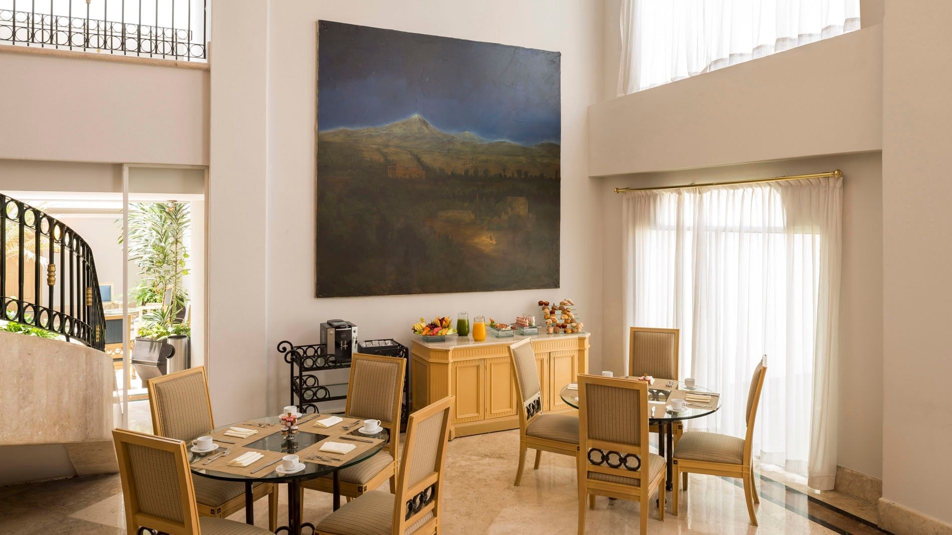 King Camino Real Club lounge with a large wall painting, dining sets, and a buffet table at Camino Real Puebla Angelopolis