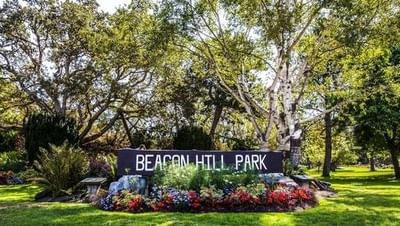 A wide shot of the Beacon Hill Park sign surrounded by colorful flowers and trees near the Embassy Inn Victoria
