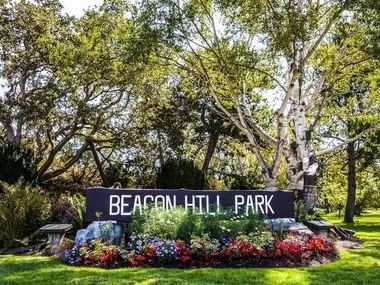 A wide shot of the Beacon Hill Park sign surrounded by colorful flowers and trees near the Embassy Inn Victoria