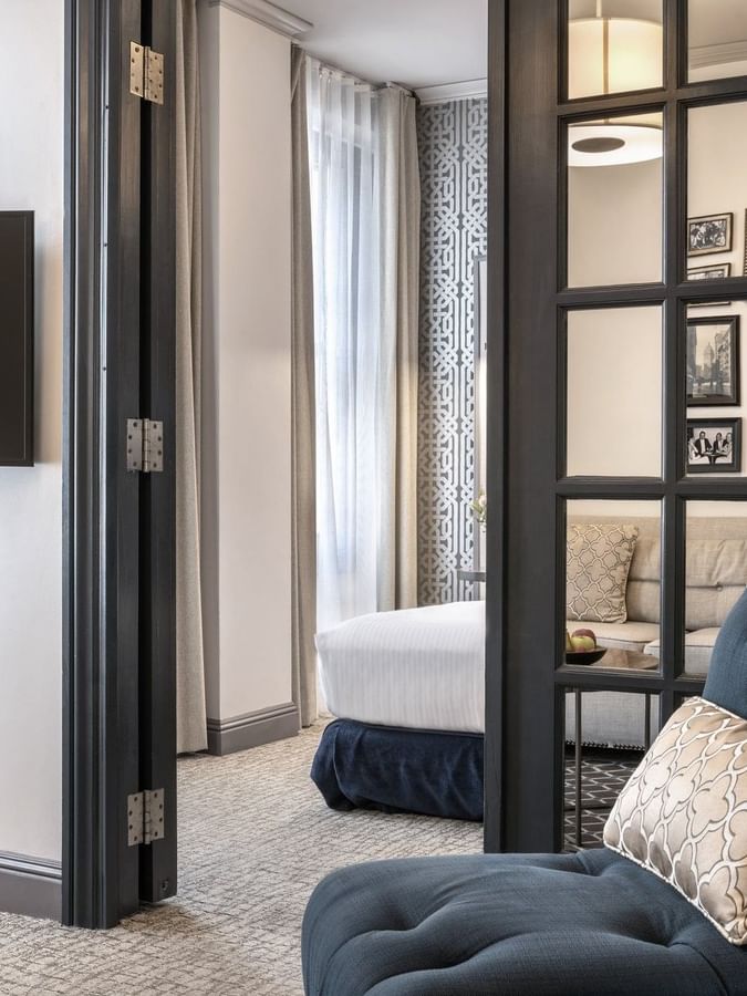 Teal armchair by a glass-paned door opening into a bedroom area in Accessible Executive Front Suite at Warwick San Francisco