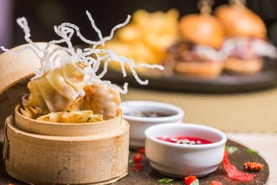 Bamboo steamers filled with dumplings, dipping sauces, and crispy noodles in Sanis Bar at Hotel Los Delfines & Casino