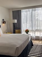 King bed with floral pillows by a striped rug under an artwork in Island View Accessible at Warwick Paradise Island Bahamas