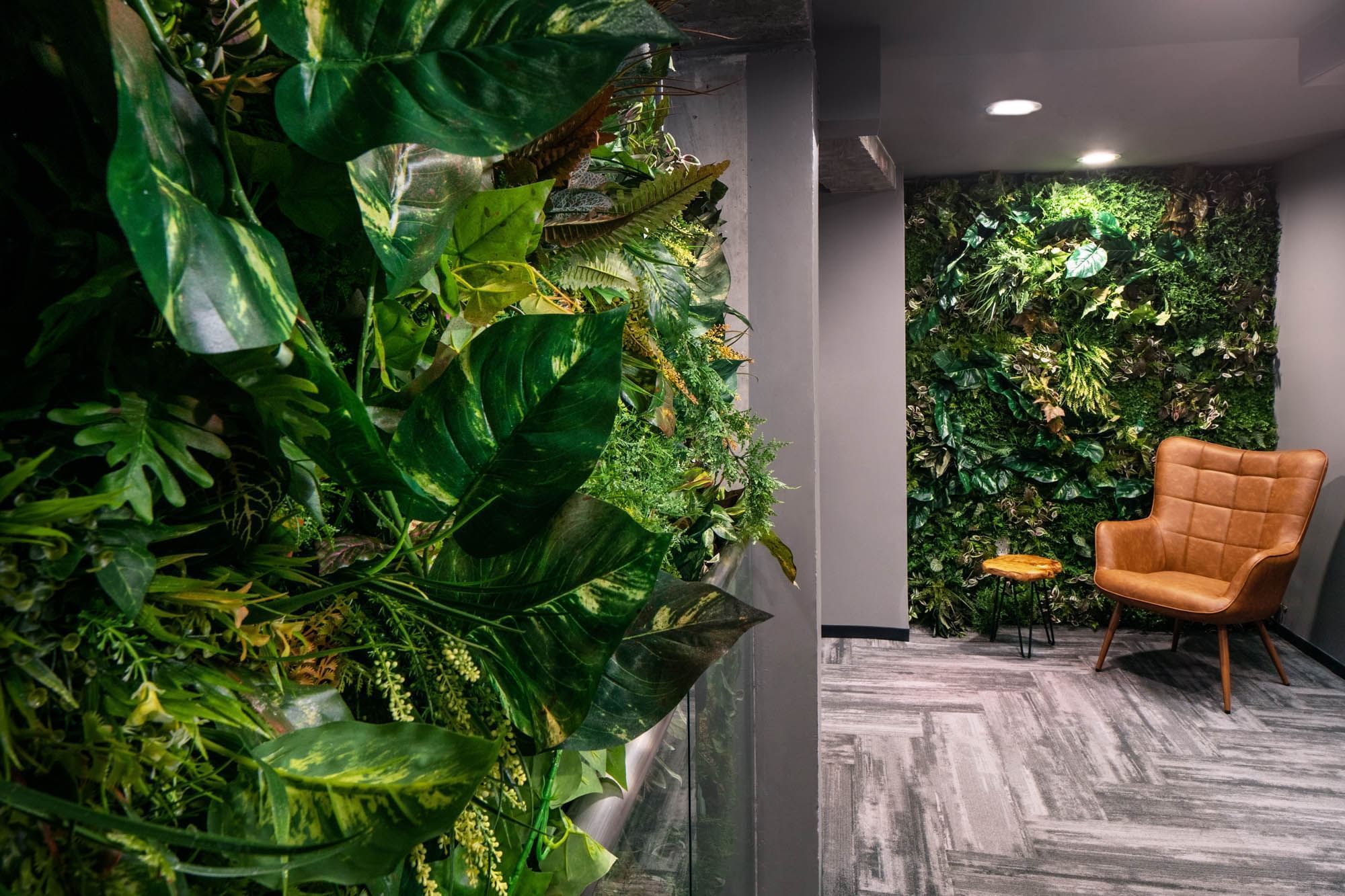 a lobby with a large plant wall, a chair, and a floor