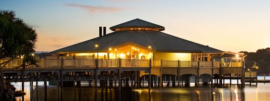 Lily’s on the Lagoon on a pier reflecting in calm water, surrounded by palm trees at the Novotel Sunshine Coast Resort