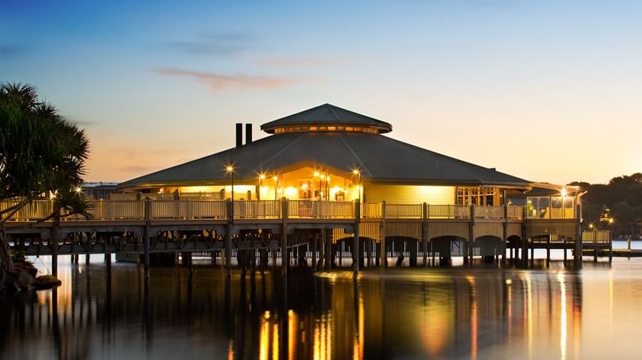 Lily’s on the Lagoon on a pier reflecting in calm water, surrounded by palm trees at the Novotel Sunshine Coast Resort