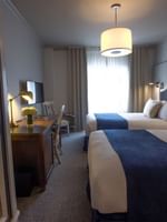 Twin Room features Two beds by a wooden desk under drum pendant lights at Warwick San Francisco