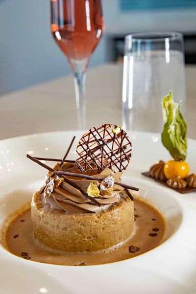 Chocolate cake with sauce and chocolate decoration on a plate with two glasses of drinks at Ellipse Grace Bay