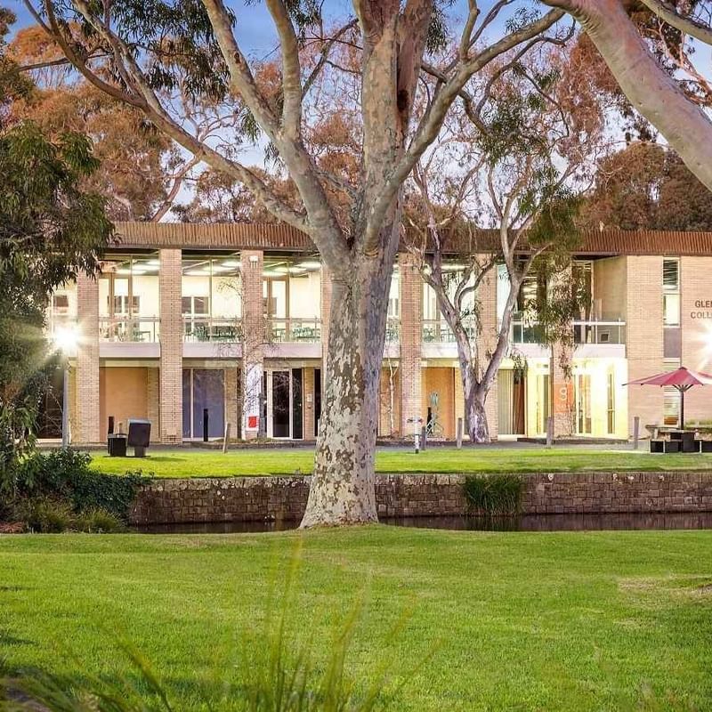 Glenn College building with lush greenery and trees at La Trobe University.