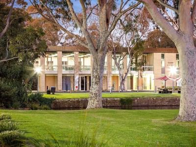 Glenn College building with lush greenery and trees at La Trobe University.