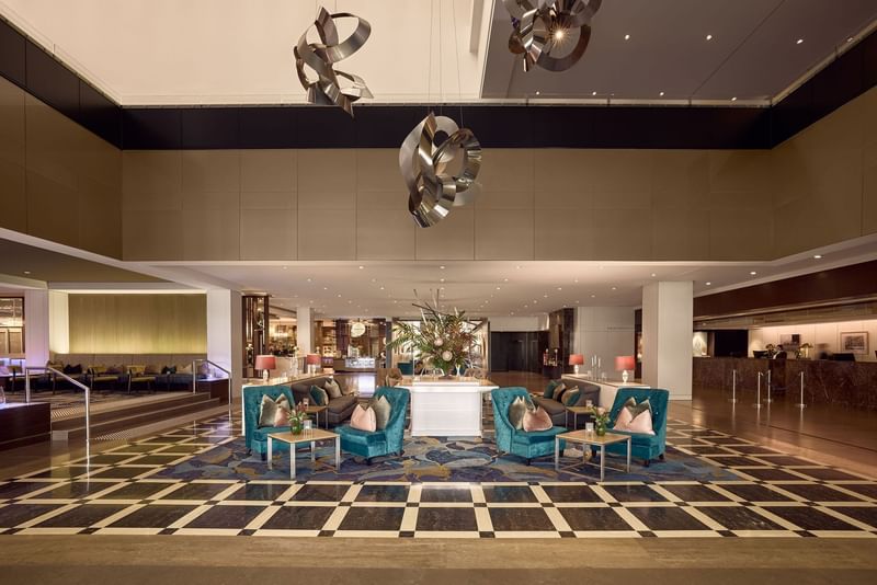 Elegant hotel lobby with teal chairs, patterned floor, and decorative lighting at Sofitel Brisbane Central