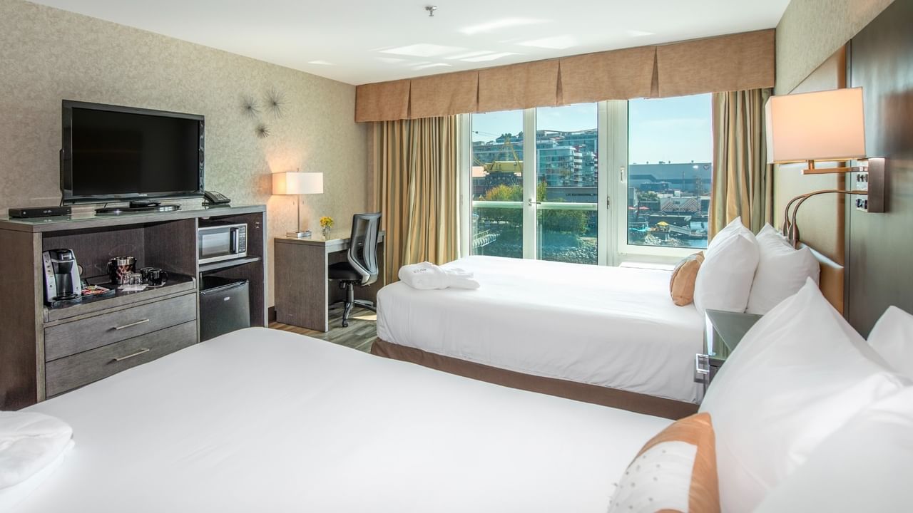 Coast Premium Two Queens with Two beds, TV, desk, and window with city view in a hotel room at Coast Lonsdale Quay Hotel
