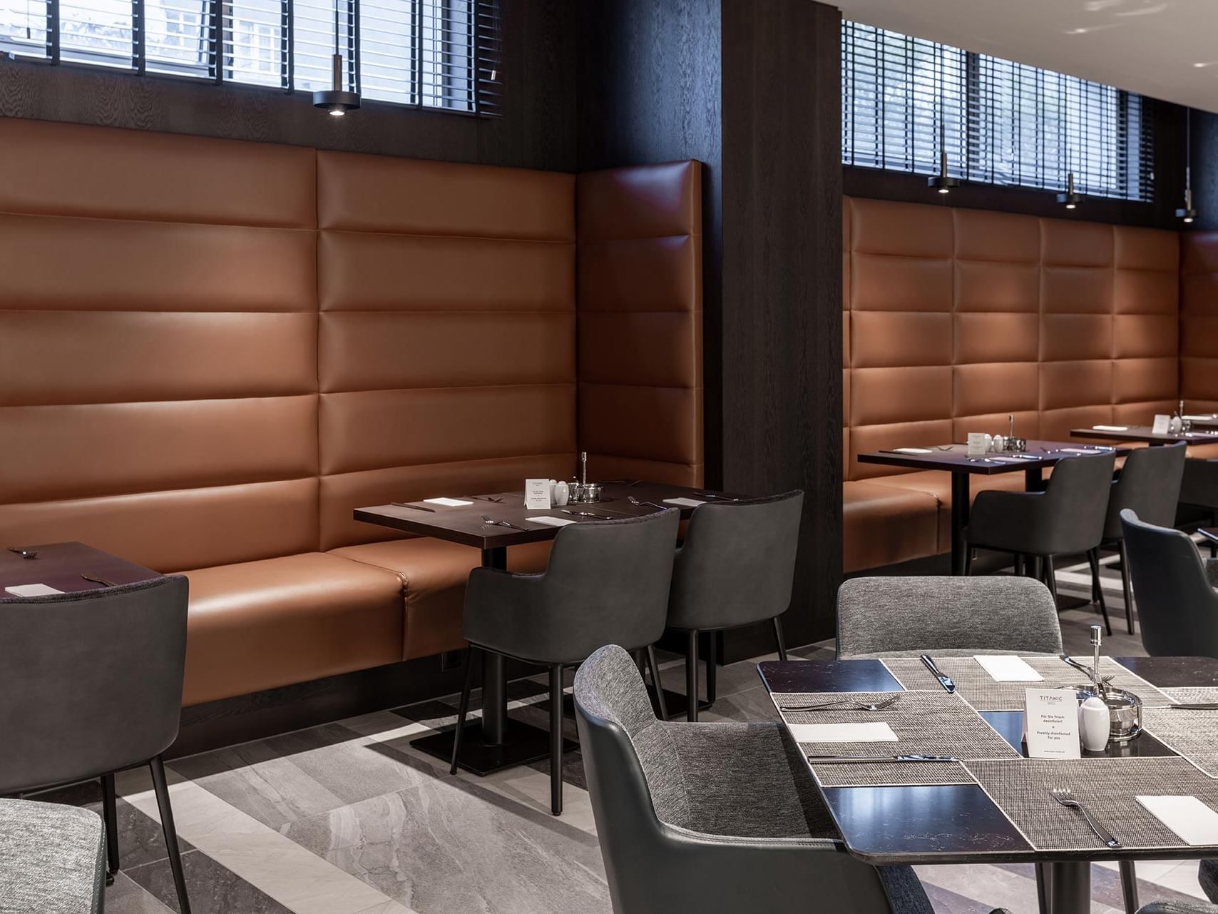 Dining area with leather banquette and tables in Breakfast Restaurant at Titanic Comfort Kurfürstendamm