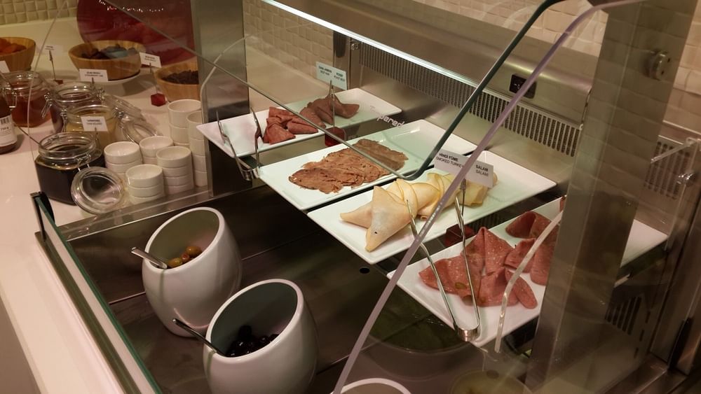 Breakfast & In-Room Dining  with Sliced meats on plates by olives in white bowls under a glass protector at Warwick Ankara