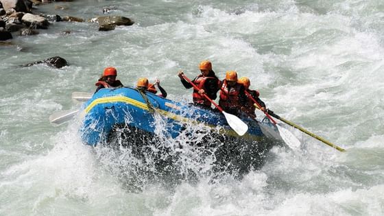 A group of rafters navigates turbulent waters in a blue raft at Aava Whistler.