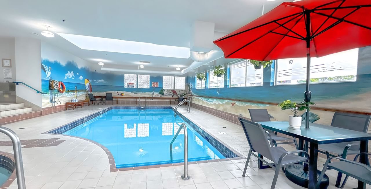 Hotel indoor pool with poolside table and umbrella
