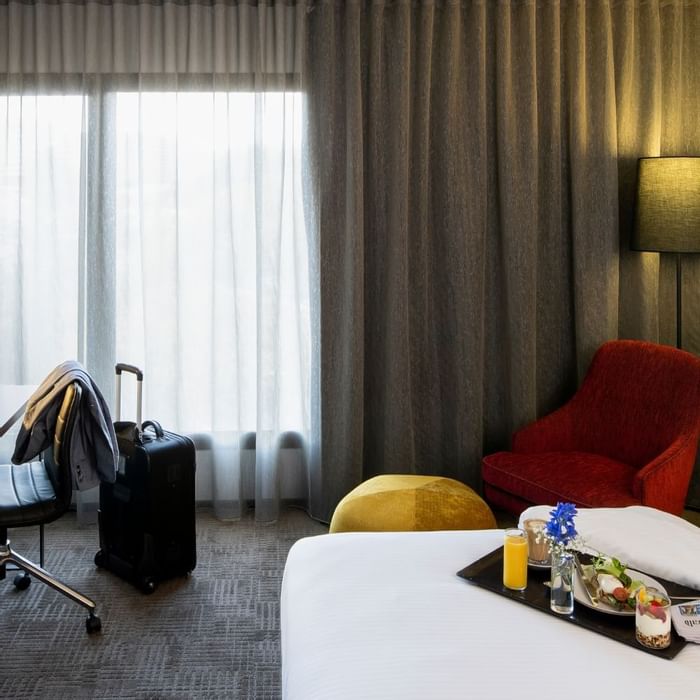 Cozy room with suitcase and breakfast tray on the bed at Novotel Sydney International Airport