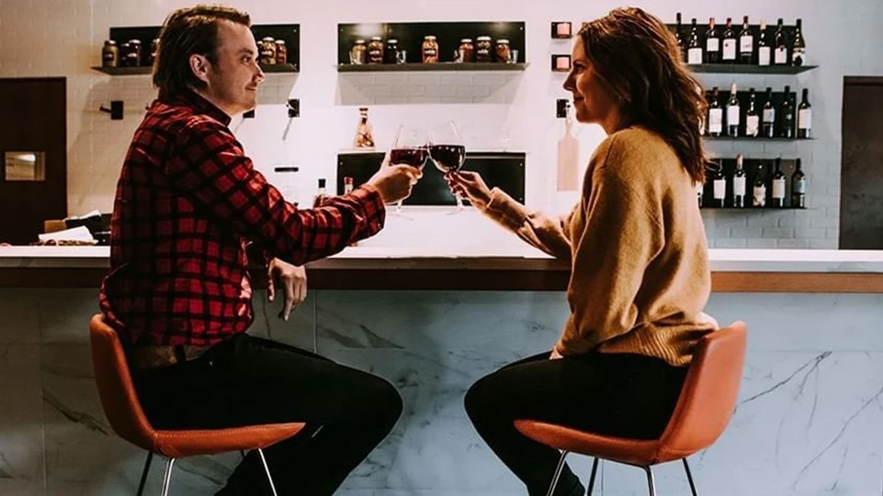 A couple cheers wine glasses at a romantic dinner restaurant in Canmore.