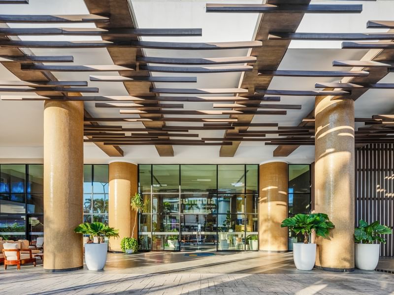 Sunvivia Mazatlán resort entrance featuring gold mosaic pillars and a stylish overhead wooden slat architectural design