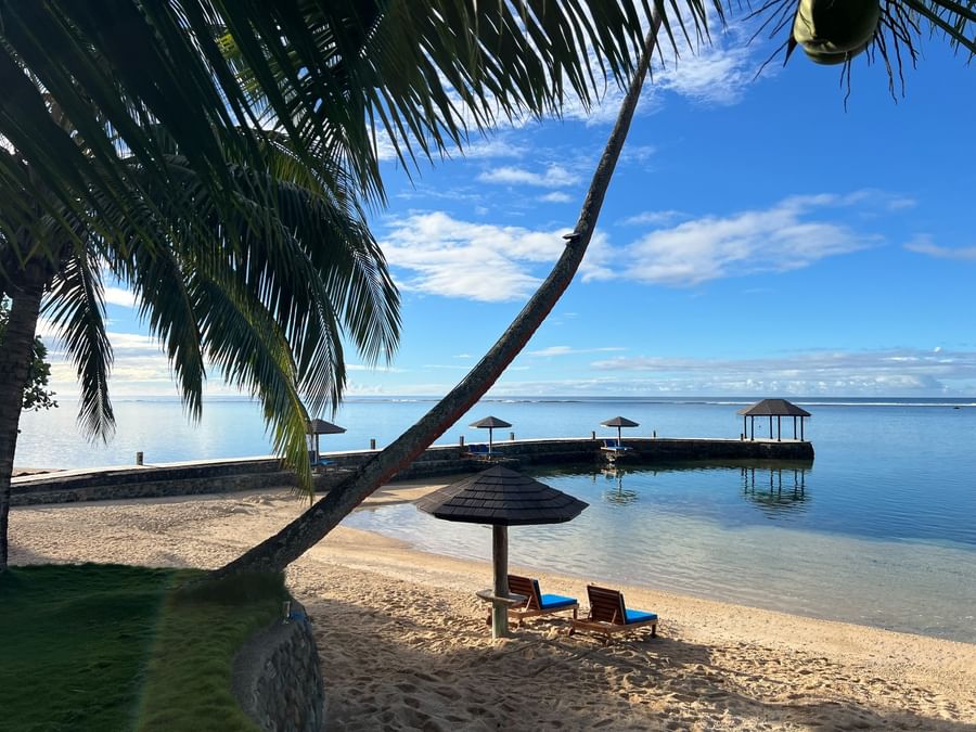 Sandy beach with lounge chairs under umbrellas and ocean view at Warwick Fiji Resort and Spa.