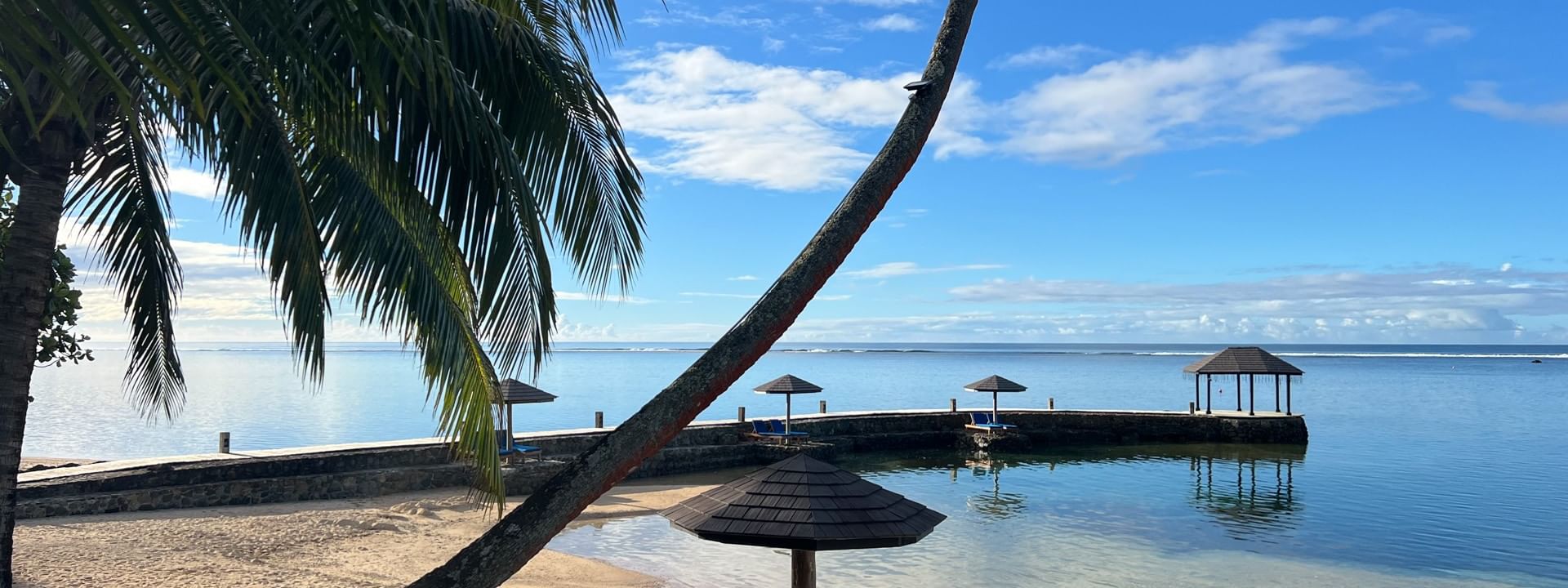 Sun loungers on sand beach with umbrellas and palm trees at Warwick Fiji Resort and Spa, Korolevu