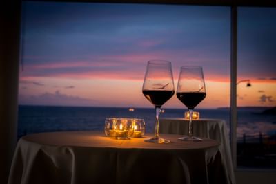Wine glasses on a table with sun setting at the background