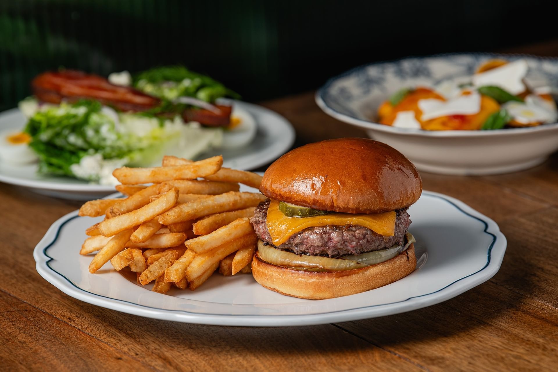 Gourmet beef burger served with French fries, dip, & a glass of red wine on a table in The Loft at Gansevoort Meatpacking NYC