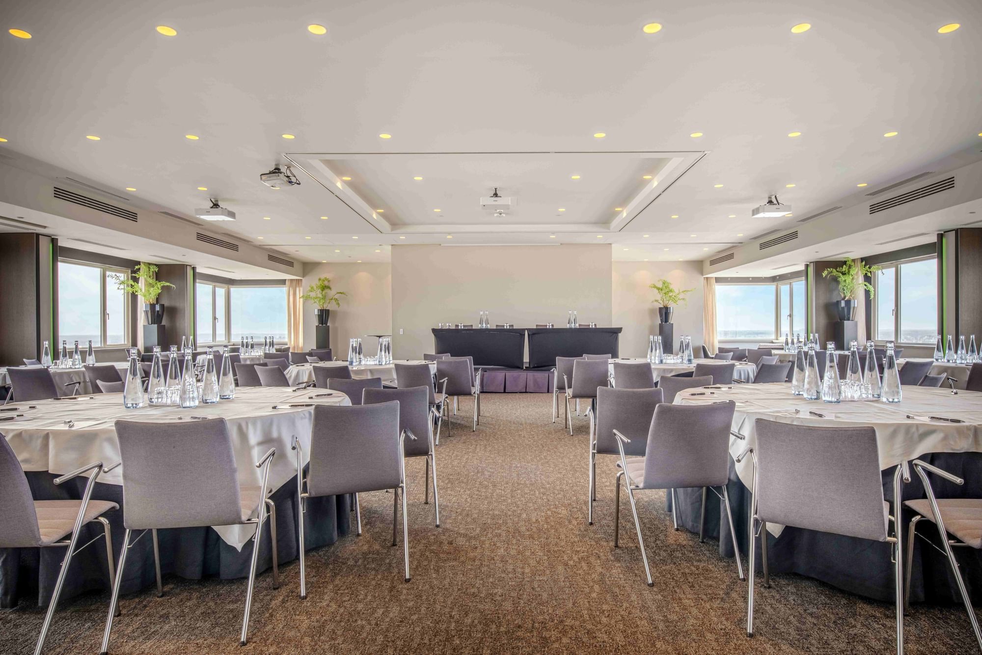 Spacious conference room with carpet floor, arranged tables and chairs at The Hotels Brussels