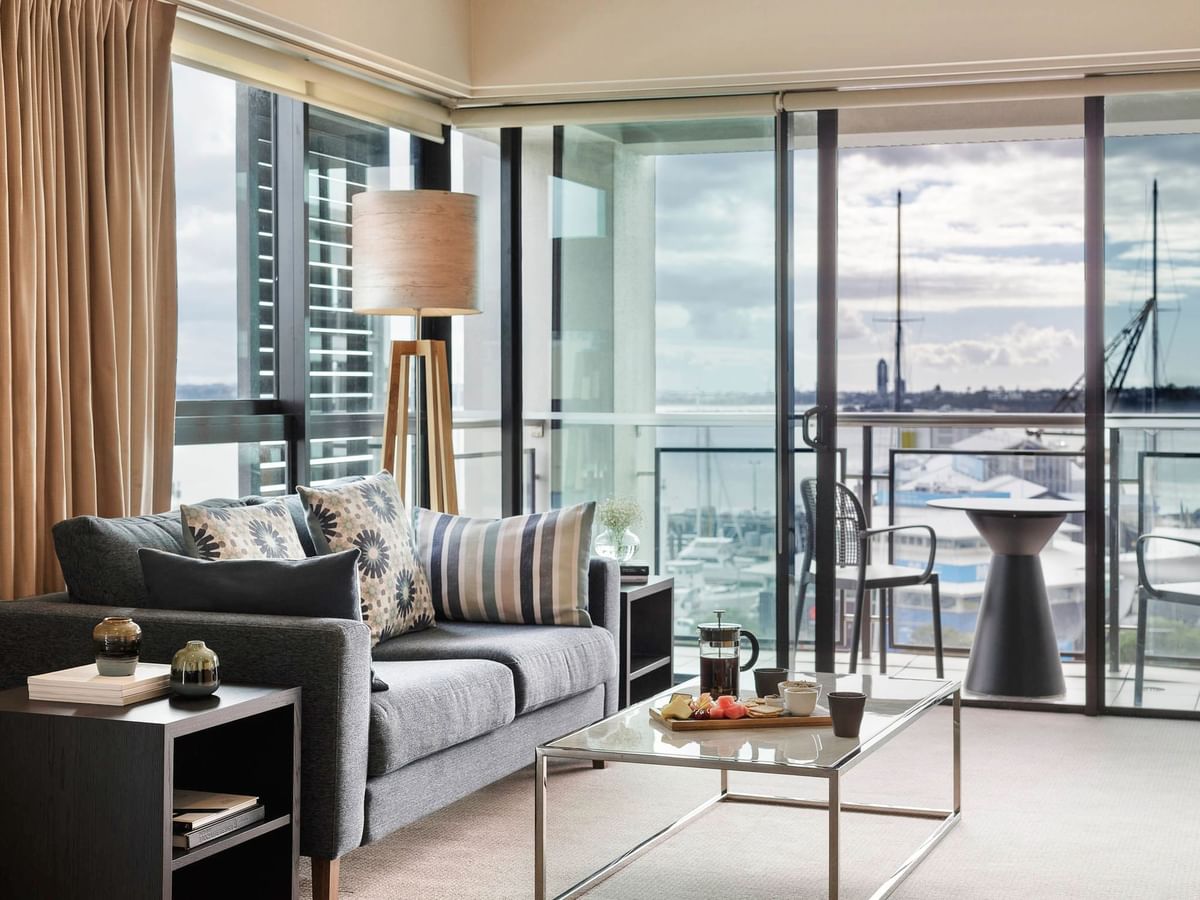Lounge with sofa and coffee table by the window in Executive Deluxe One Bedroom Suite at The Sebel Auckland Viaduct Harbour