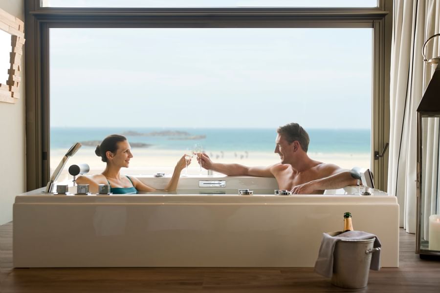 Couple enjoying Champagne in a bathtub with a Sea view at Le Grand Hôtel des Thermes