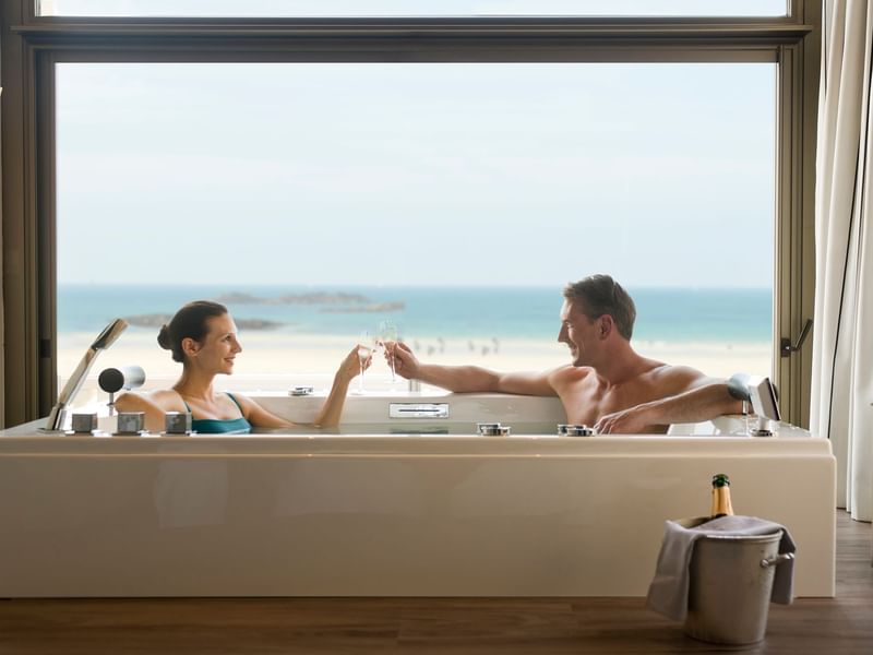 Couple enjoying Champagne in a bathtub with a Sea view at Le Grand Hôtel des Thermes