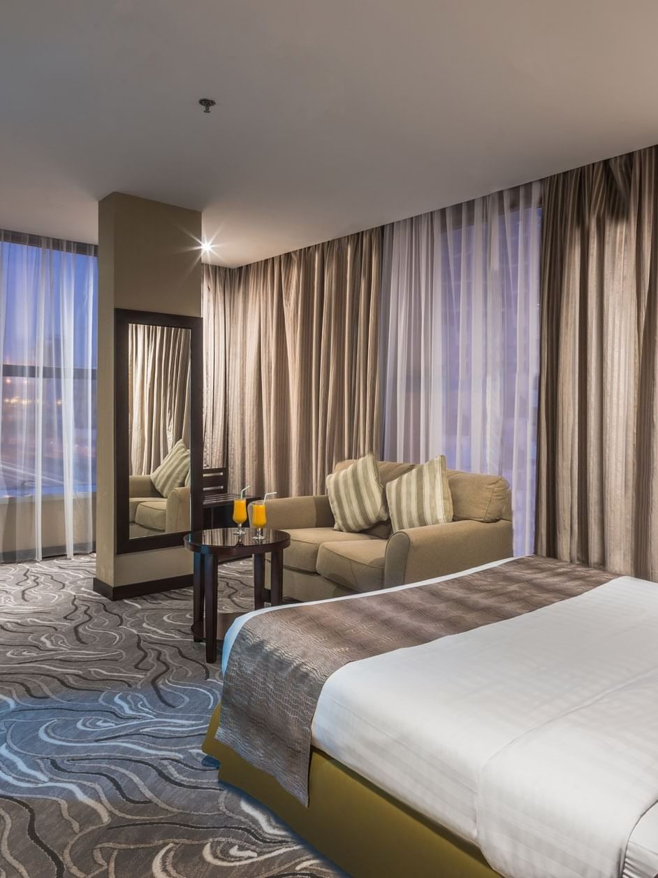 Modern lounge chair by a tall mirror under soft ceiling lights in Executive Suite Sea View at Naviti by Warwick Al Khobar