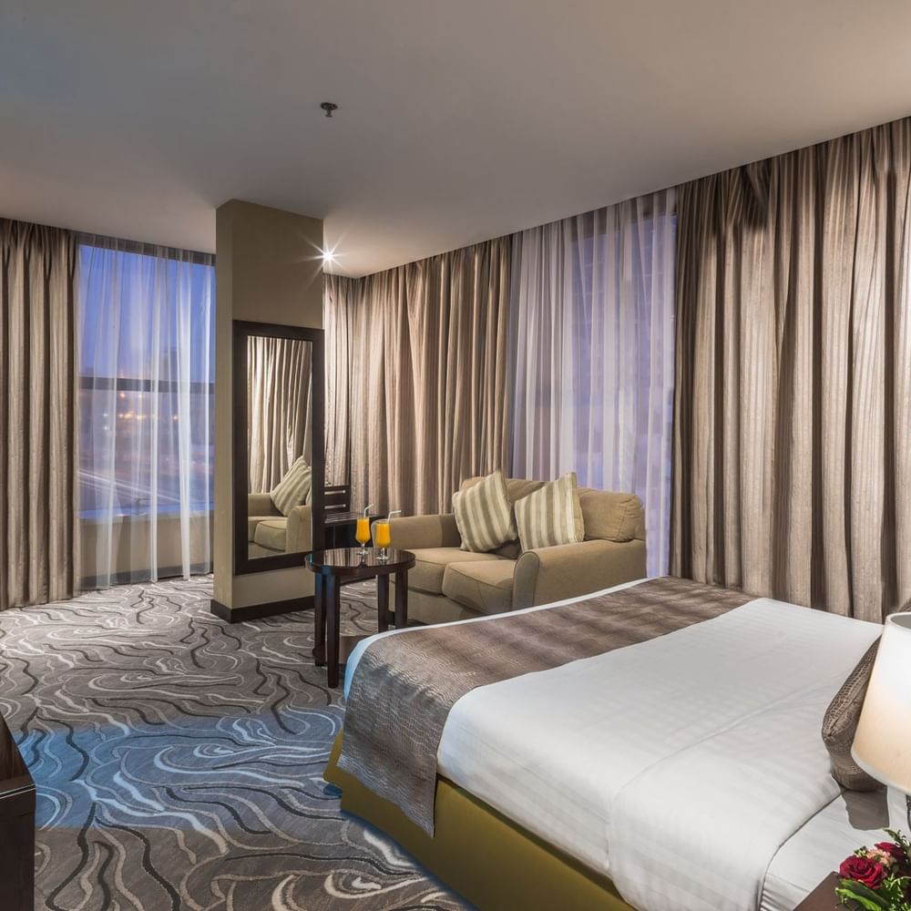 سرير مع طاولة جانبية وأريكة في الجناح التنفيذي المطل على البحر في فنادق ومنتجعات وارويك