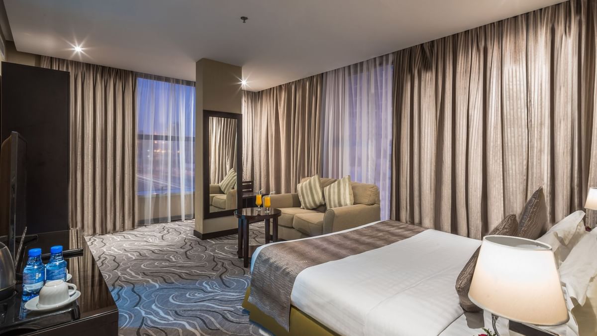 Modern lounge chair by a tall mirror under soft ceiling lights in Executive Suite Sea View at Naviti by Warwick Al Khobar