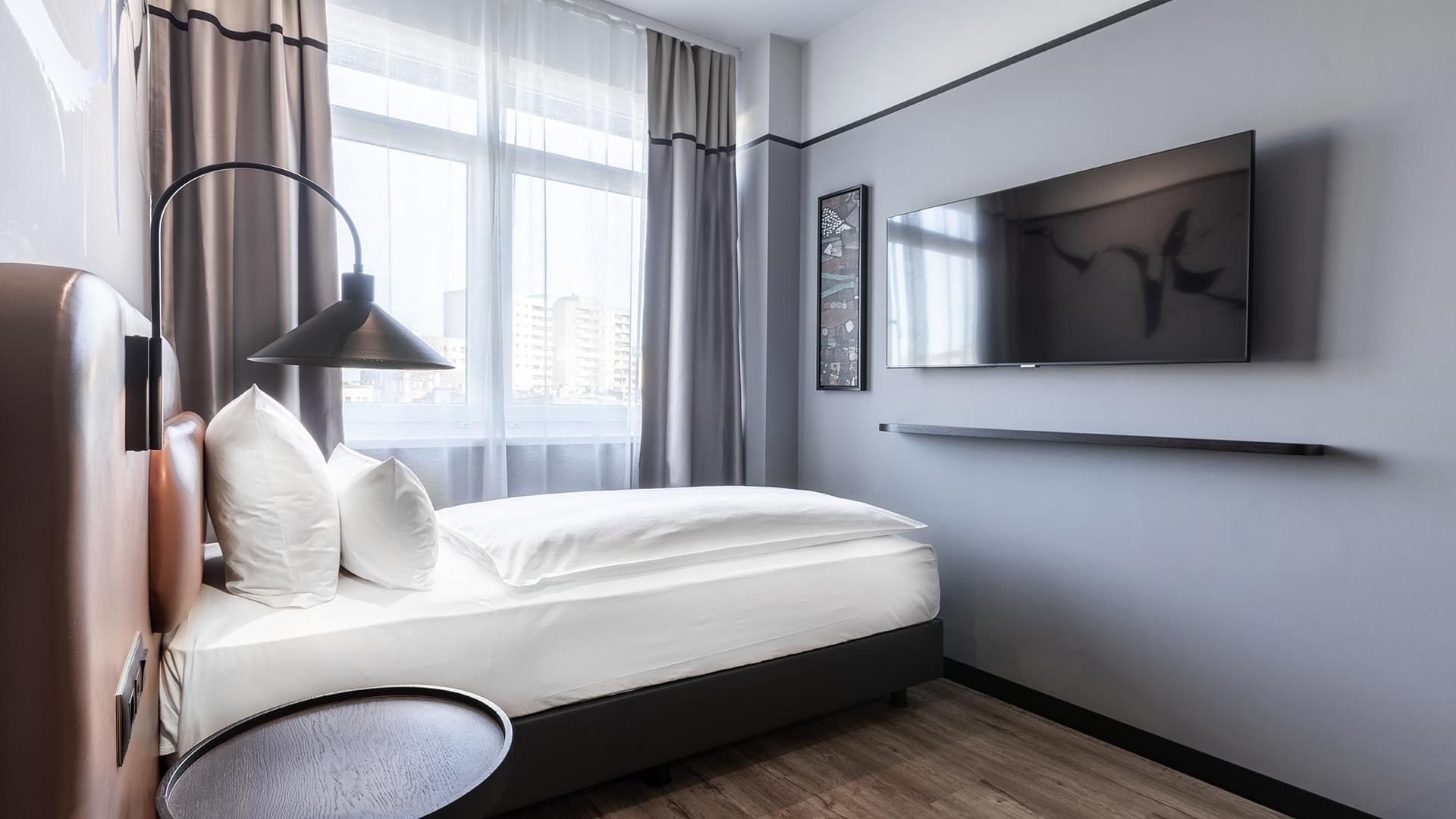 A single bed with TV in Classic Single Room at the Titanic Comfort Kurfürstendamm