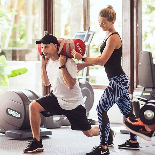 A fitness trainer guiding a person in the gym at Marbella Club
