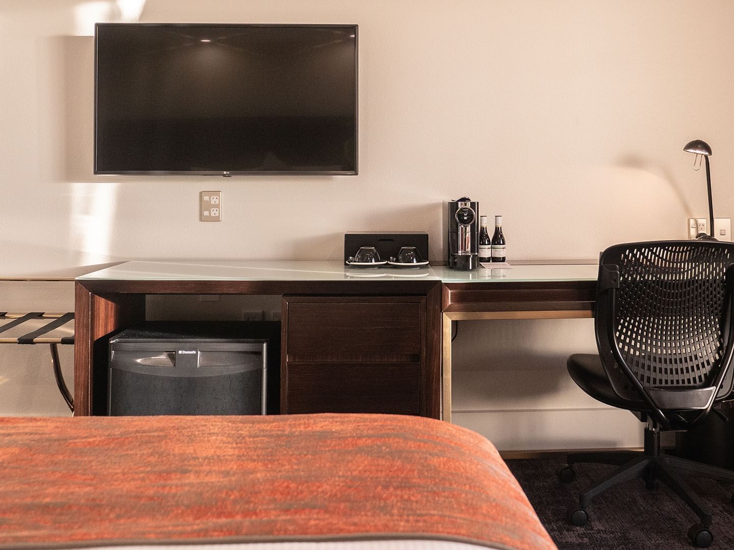 TV by a work desk facing the king bed in Deluxe Rooms at James Cook Grand Chancellor
