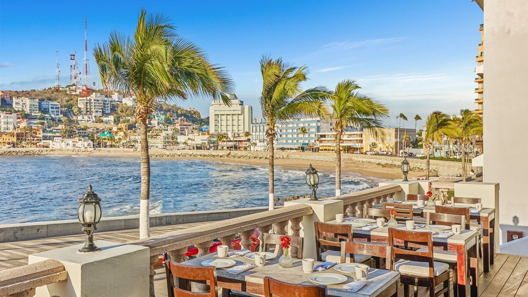 Outdoor dining area with tables and chairs offering a stunning ocean view at Curamoria Collection