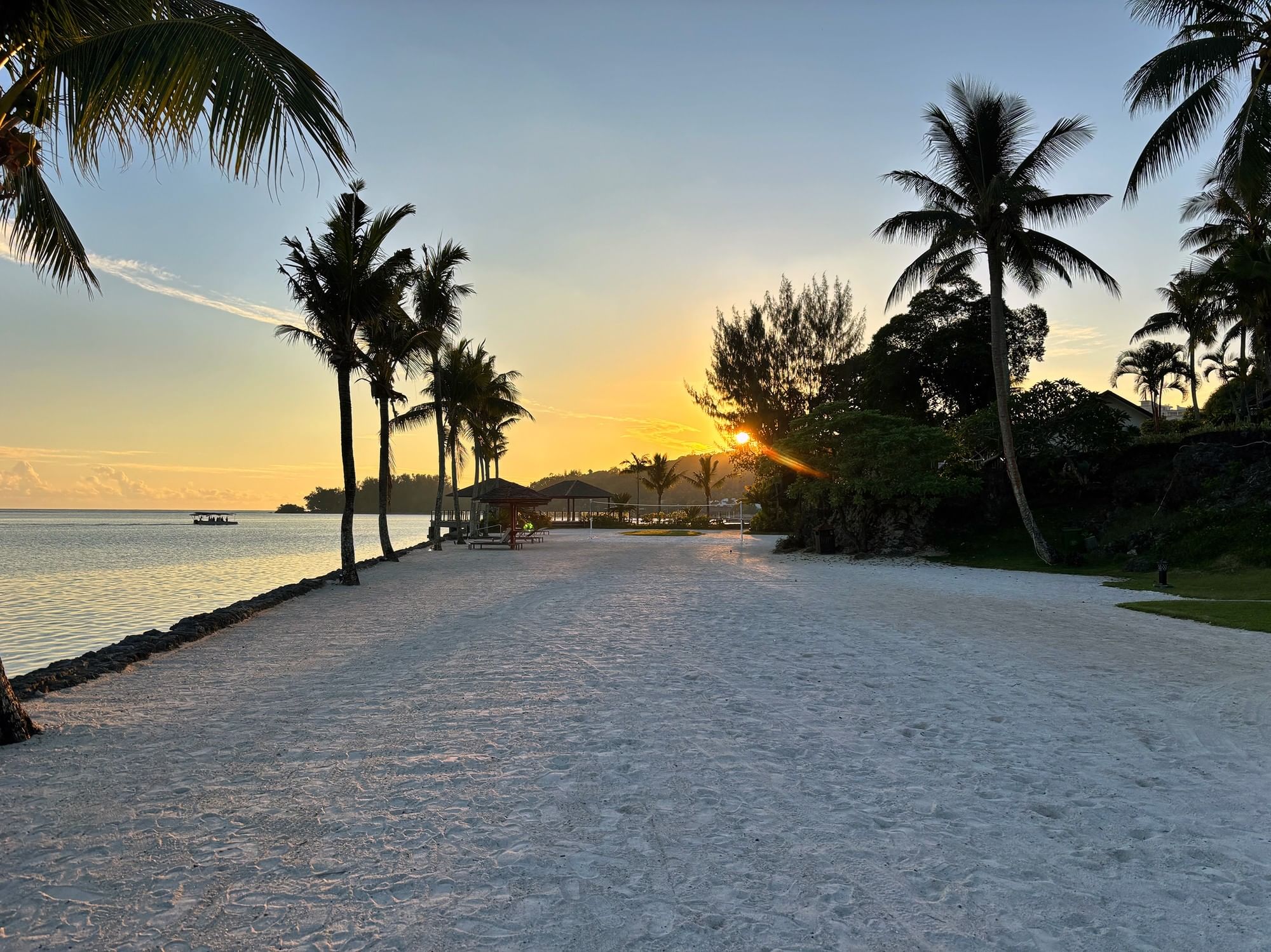 Sandy beach at sunset with palm trees and ocean view at Warwick Corporate